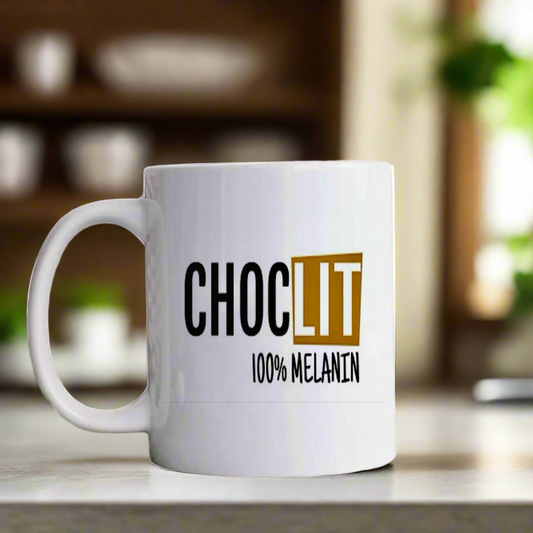 The Choc-Lit Mug by Kreative Kreationz sits on a kitchen counter, displaying “CHOC LIT 100% MELANIN” in bold black and gold letters, with shelves and plants softly blurred in the background.