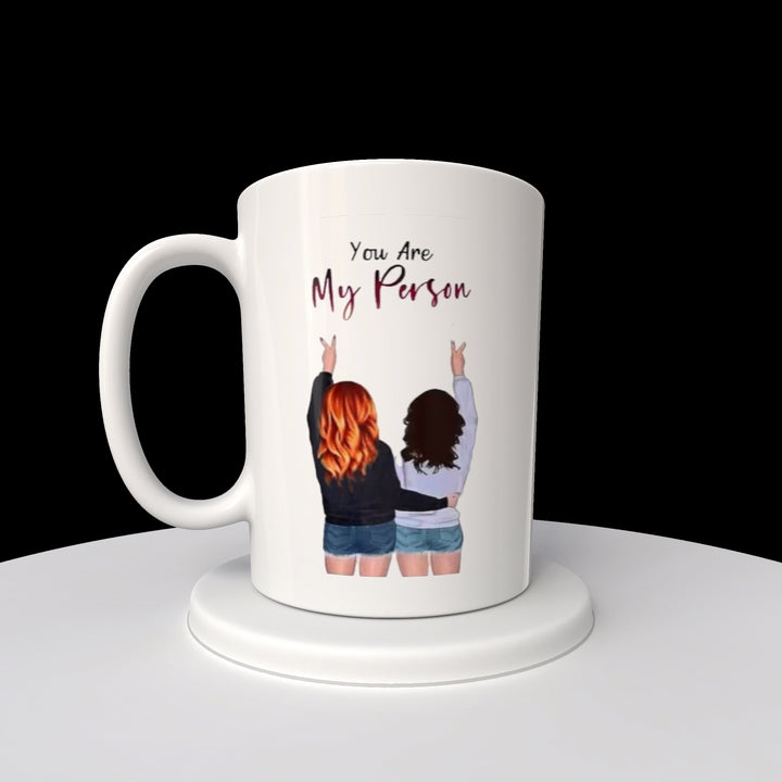 The Kreative Kreationz "Your My Person | Best Friend 20oz Mug" features a sublimated design with an illustration of two people from behind, fingers making peace signs, and the phrase "You Are My Person" above, ensuring lasting quality and sentiment.