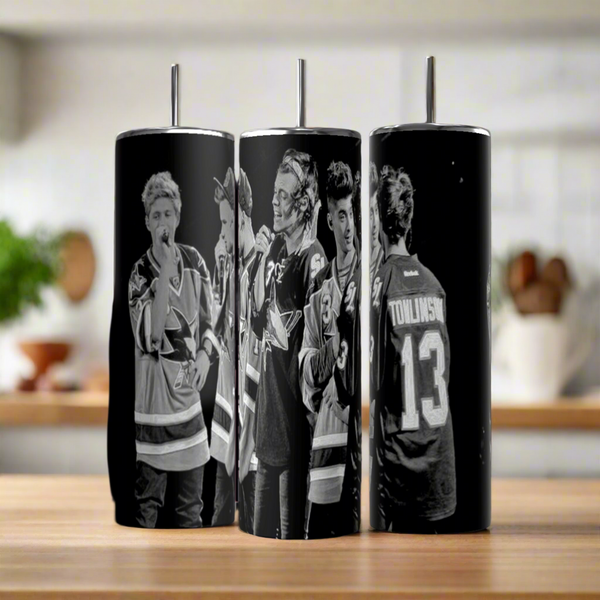 Three Kreative Kreationz One Direction B&W 20oz Stainless Steel Tumblers, featuring black-and-white images of people in hockey jerseys (including "TOMLINSON 13"), are displayed side-by-side on a wooden surface.
