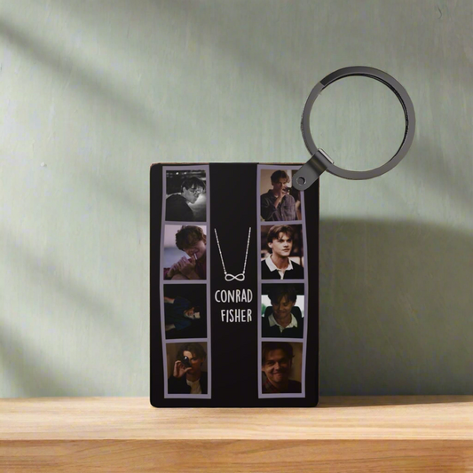A display plaque with multiple photos of a young man named Conrad Fisher, a necklace graphic, and the "Team Conrad Inspired Keychain" by Kreative Kreationz, all arranged on a wooden surface against a light gray wall.