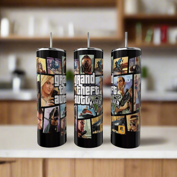 Three Kreative Kreationz Grand Theft Auto 20oz Tumblers with stainless steel straws are shown on a kitchen counter, each featuring vibrant designs and the "Grand Theft Auto V" logo in a luxury-inspired style.