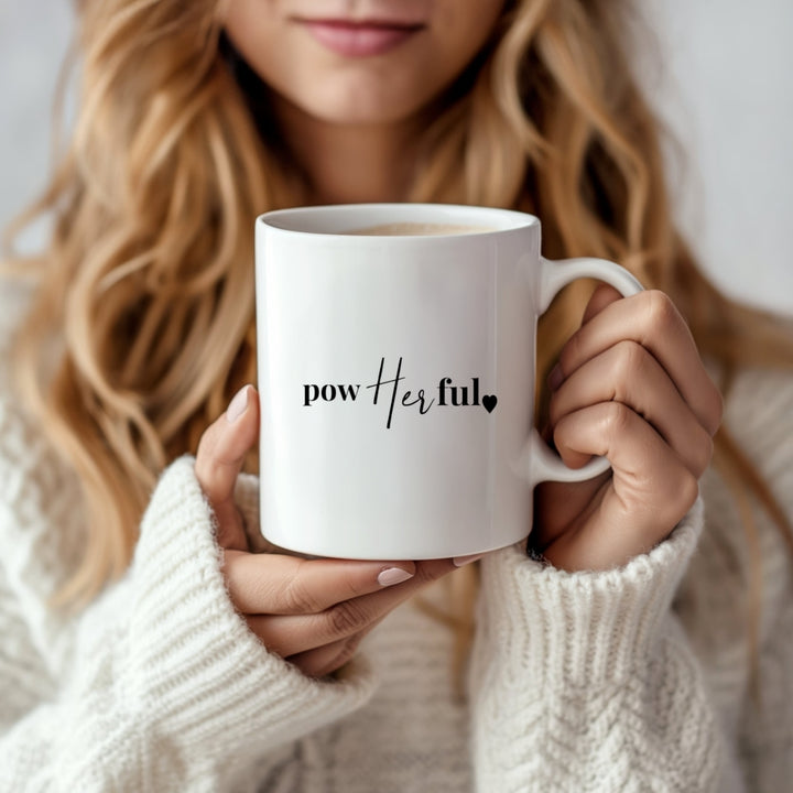 A woman with long wavy hair in a cozy white sweater holds the Vibes Mug by Kreative Kreationz, featuring "powerful" with "Her" in bold script and a heart—a dishwasher-safe ceramic mug designed to inspire.