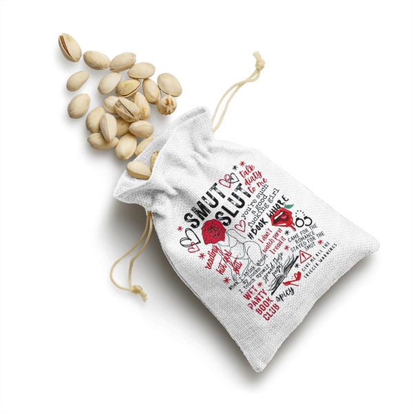 The Smut Canvas Satchel by Kreative Kreationz is a small white cotton drawstring bag decorated with doodles and cheeky phrases like “Smut Sluts” and “Spicy”—a playful bachelorette party gift perfect for holding pistachios.