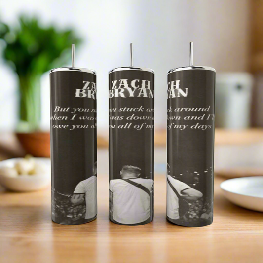 The Kreative Kreationz Zach Bryan Lyric 20oz Tumblers feature luxury-inspired stainless steel designs with black and white images, partial song lyrics, and “ZACH BRYAN” text. Photos show a man playing guitar on a wooden table.