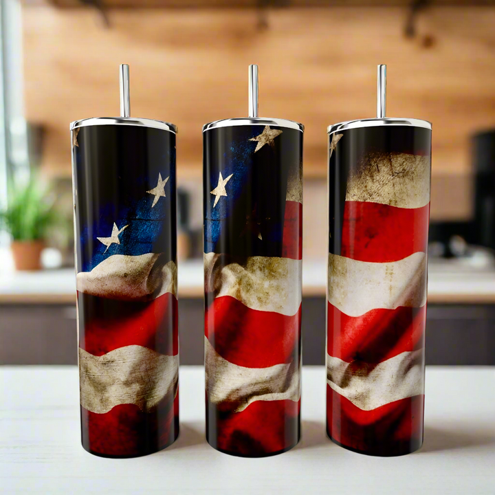 Three Kreative Kreationz American Flag 20oz Skinny Tumblers, each with a straw and vintage flag design, sit on a counter in front of a softly blurred indoor kitchen setting.