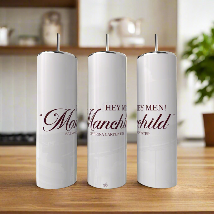 Three eco-friendly, white 20oz Manchild Sabrina Carpenter tumblers by Kreative Kreationz, each with a metal straw and elegant "Hey Men! Manchild" script, are displayed on a kitchen counter.