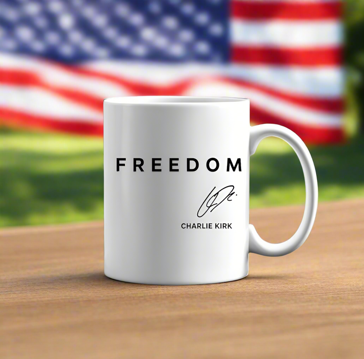 The Freedom Charlie Kirk Mug by Kreative Kreationz features “FREEDOM,” a signature, and “CHARLIE KIRK” on white ceramic. Set against a waving American flag, it's a patriotic statement piece for any space.