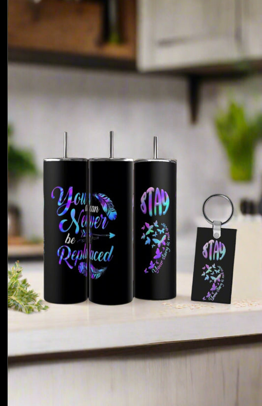 Three black tumblers with feather, arrow, and inspirational quotes, plus a “STAY” butterfly keychain, from Kreative Kreationz's Suicide Awareness Gift Set, sit on the counter—an uplifting reminder of hope.