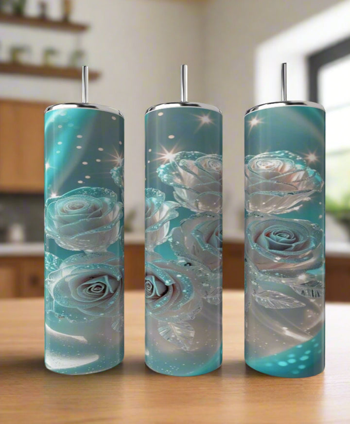 Three Kreative Kreationz Glowing Roses 20oz Stainless Steel Tumblers with straws, featuring glowing blue and silver roses and leaves, stand on a wooden surface in a softly blurred kitchen setting.