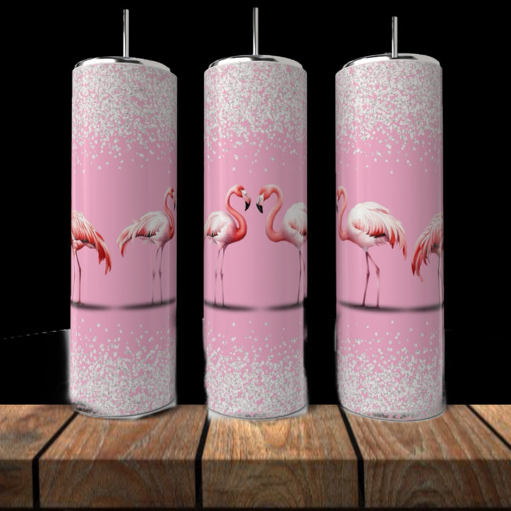 Three Kreative Kreationz Pink Flamingo 20oz Tumblers with silver lids and straws display illustrated flamingos and white glitter accents, arranged on wood with a black background.