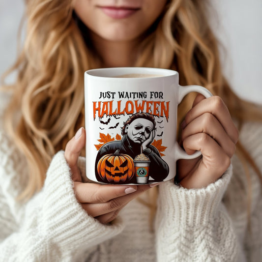 A woman in a cozy white sweater holds the Kreative Kreationz “Waiting For Halloween” ceramic mug, which features a spooky Michael Myers design with vibrant colors, bats, a jack-o’-lantern, and the phrase "Just Waiting for Halloween.