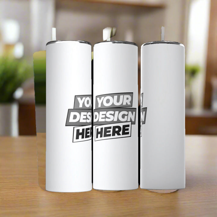 Three Kreative Kreationz Customized 20oz Stainless Steel Tumblers sit on a wooden table, each featuring "YOUR DESIGN HERE" in bold black text, highlighting their customizable nature against a softly blurred background.