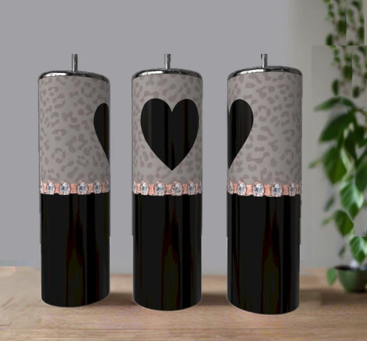 Three black and gray Kreative Kreationz Heart Rhinestone 20oz Skinny Tumblers feature leopard print bands, a heart design on the center tumbler, and faux gemstones, displayed on a wooden surface with a plant in the background.