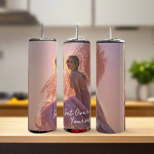 Three Kelsey Ballerini Over Yourself 20oz tumblers by Kreative Kreationz, each with an image of a woman in a pink dress and sunglasses plus “Get Over Yourself” text, sit with metal straws on a wooden surface against a blurred kitchen backdrop.